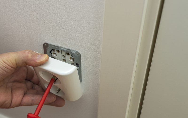 Close up view of man repairing white light switch.  Electricity concept. Sweden.